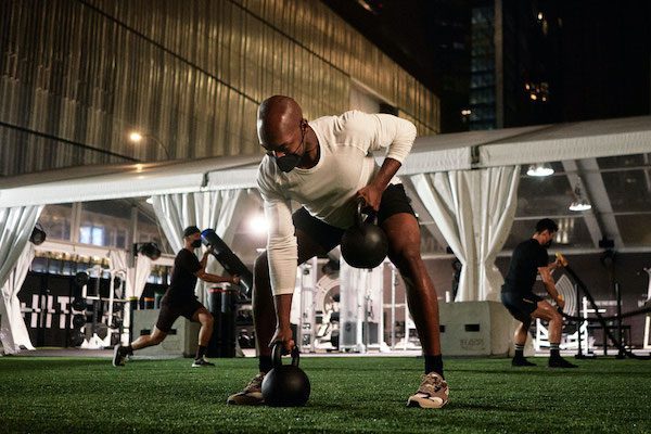 Man doing weight training at outdoor Equinox gym