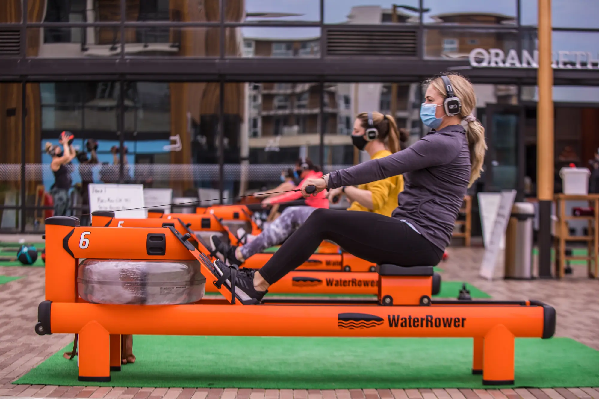 Women on rowing machine wearing Sound Off headphones