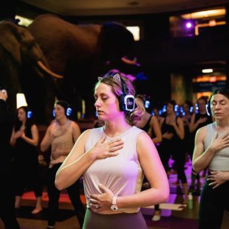 Women participating in an indoor yoga class with Sound Off silent disco headphones